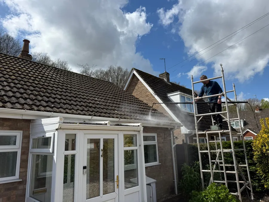 Technician cleaning a gutter and roofline from a scaffold tower